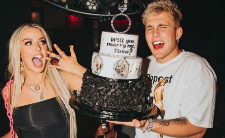 tana shocked with happiness and jake standing with a cake that says will you marry me tana?